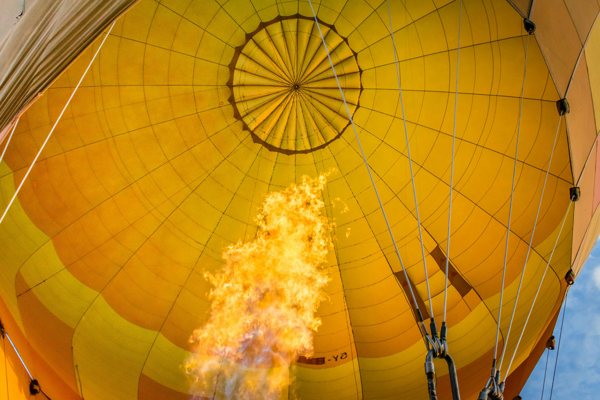 Close up of a yellow hot air balloon with fire in the center