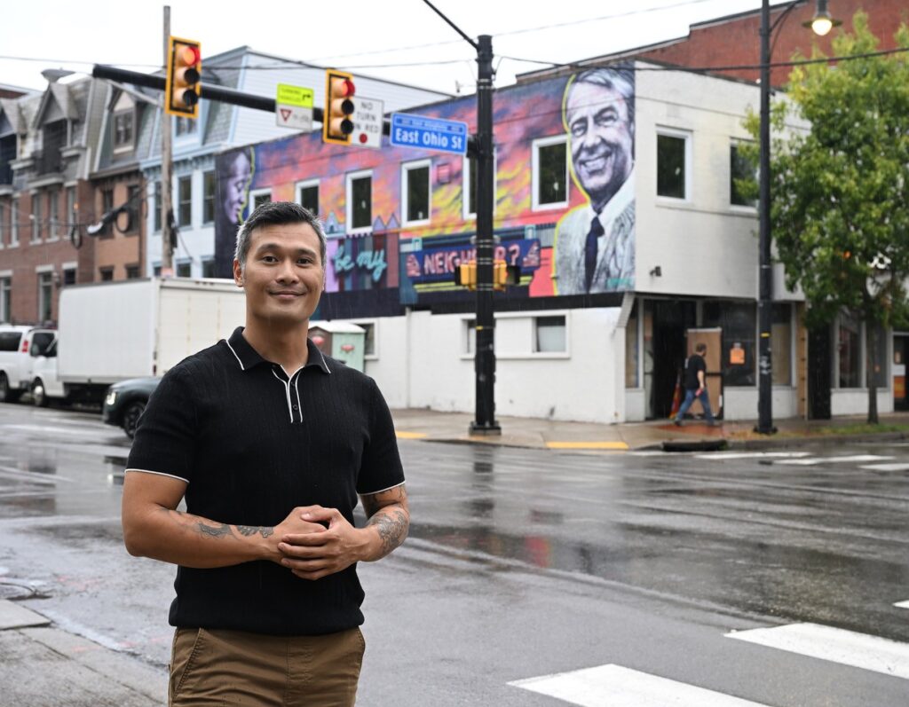 Rafael on the corner of of street with his restaurant in the foreground.