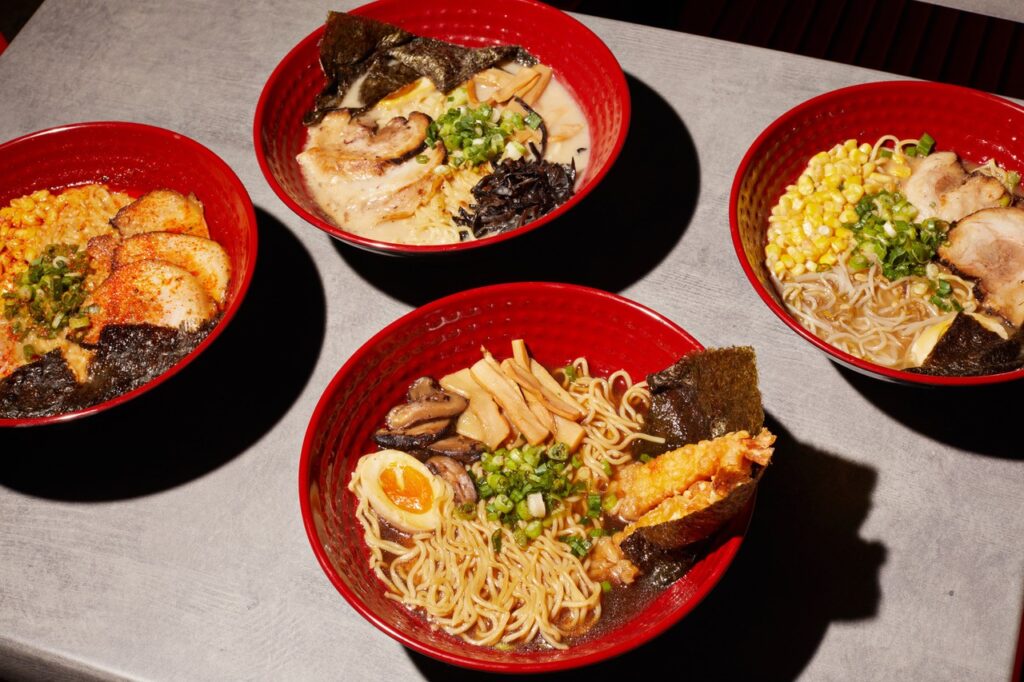 Various dishes from Teachana of the Ramen variety with bright red bowls. 