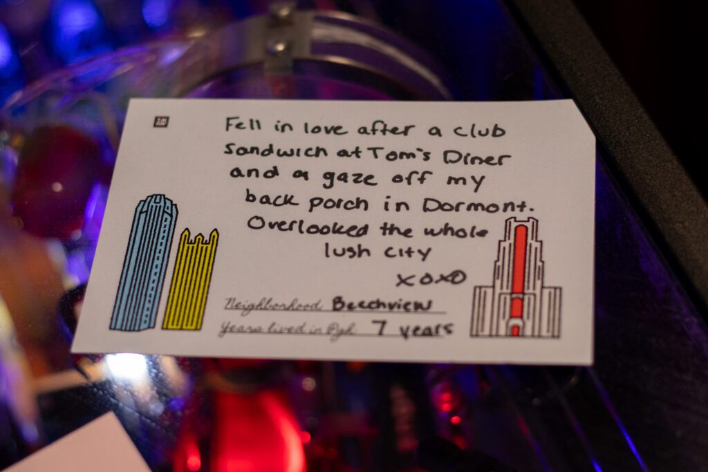 A post card with a love letter to Pittsburgh that reads "Fell in love after a club sandwich at Tom's diner and a gaze off my back porch in Dormont." 