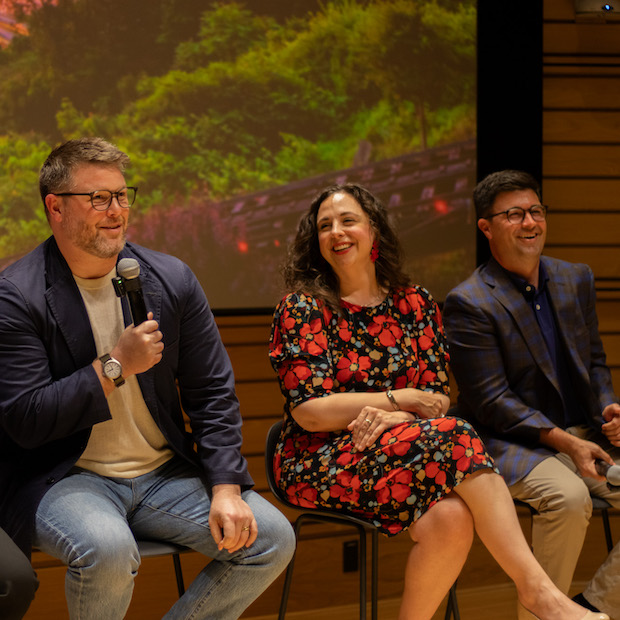 Dan Law, Jen Apicella, and Corey O'Connor laughing on stage during a panel discussion