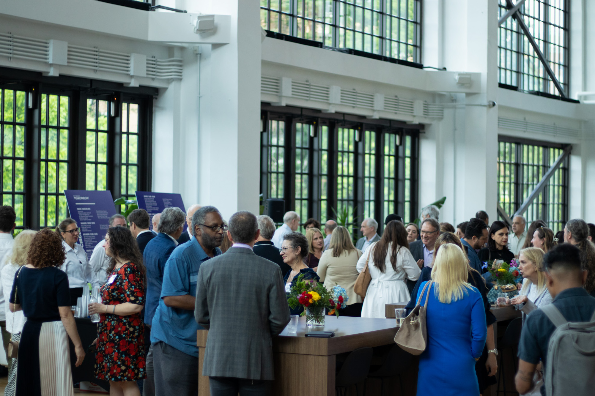 A crowd of people in a building with big windows.