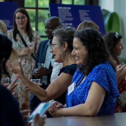 A woman smiling in a crowd while in a conversation.