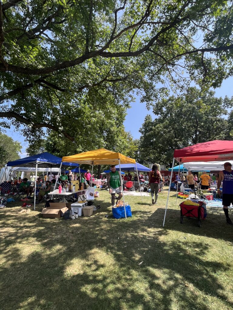 Various colored tents with kickball teams relaxing or playing games at the event in between games.