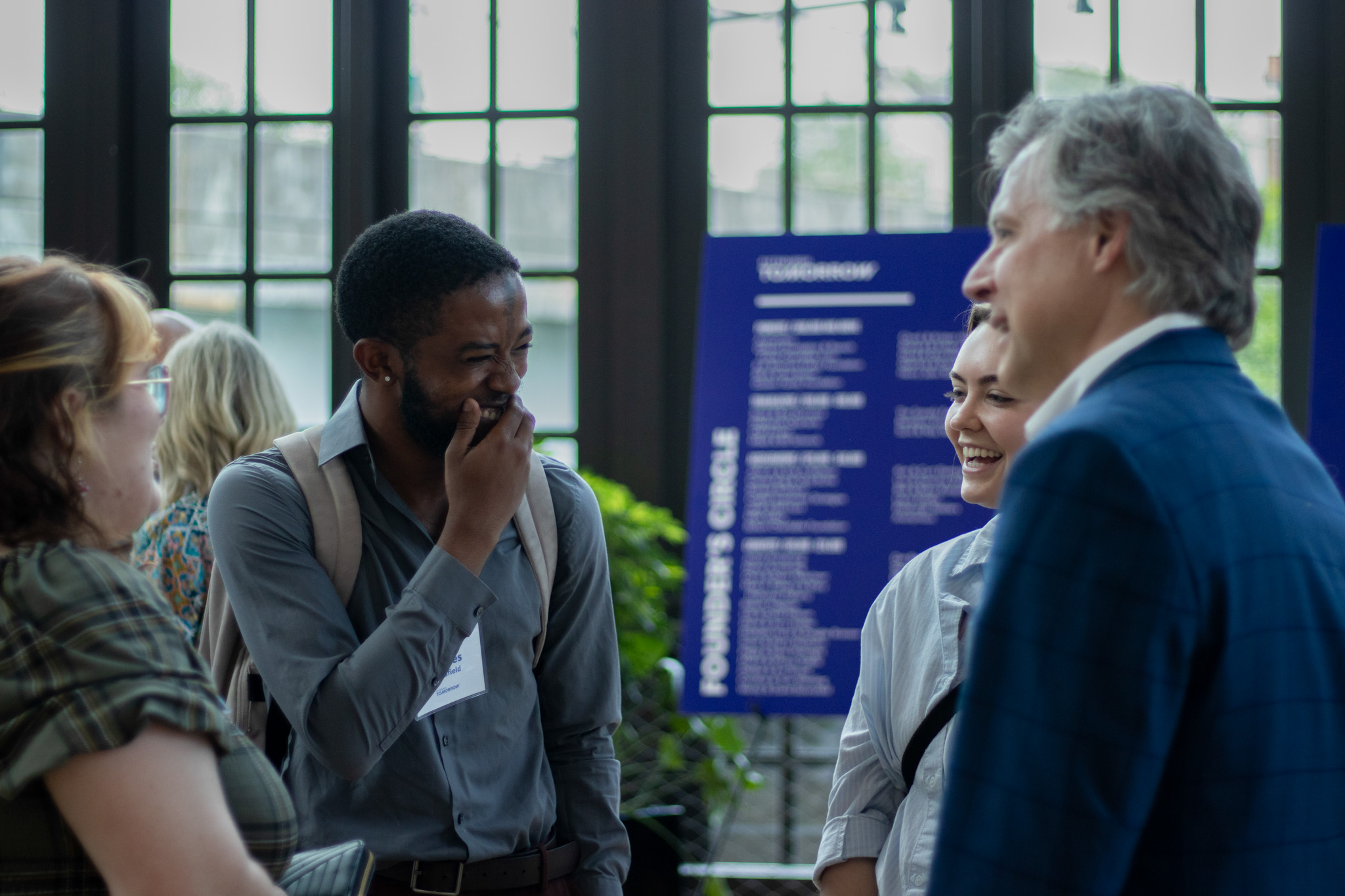 Charles laughs while chatting with a group of people.