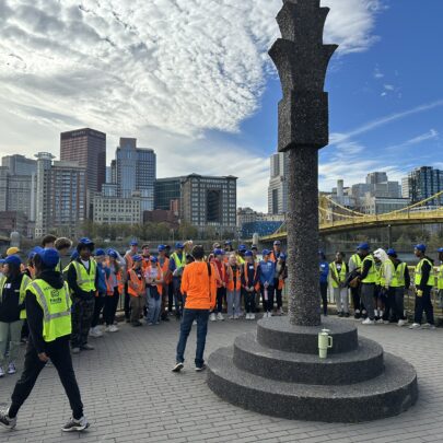 A crowd gathers along the riverfront to pick up litter