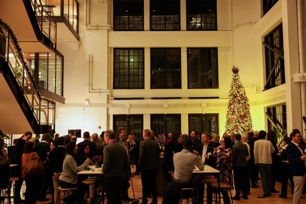 A large crowd gathers in an assembly hall lit by a Christmas Tree