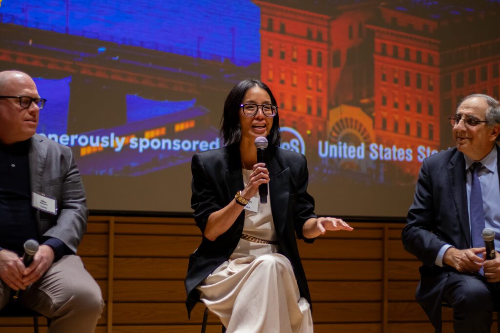 Jocelyn Lai gestures and holds a microphone on stage